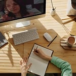 How the Ghostwriting Process Works: Woman writing in notebook while conducting a Zoom interview.